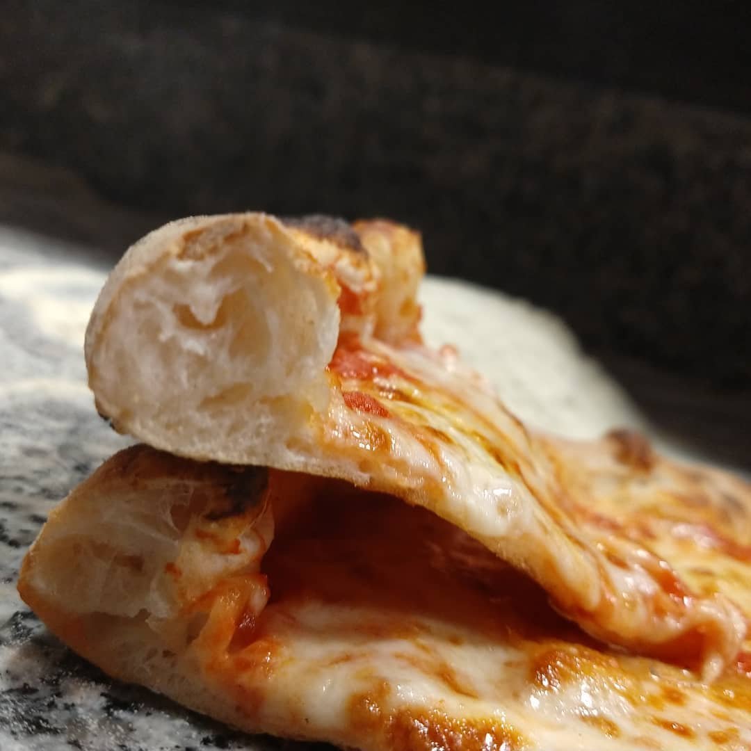 Sezione della pizza con filo di mozzarella e bordo alveolato